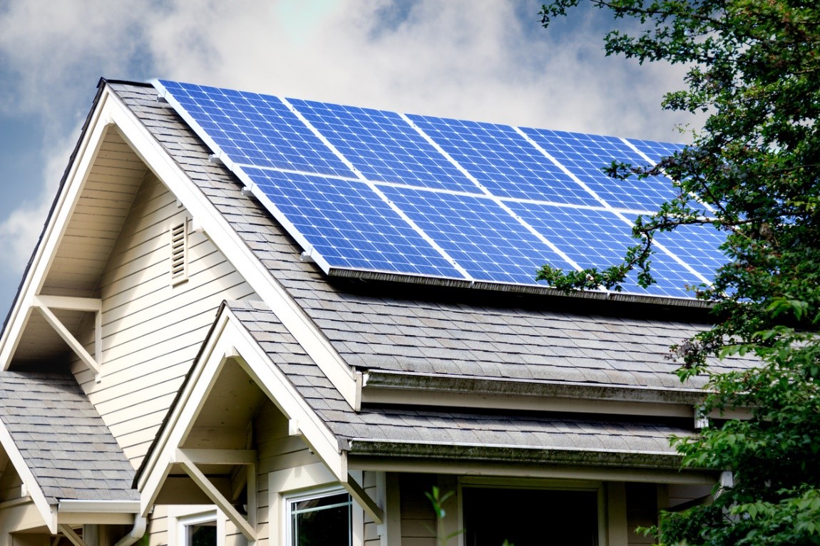 Podpisywanie umowy ubezpieczenia instalacji PV Osoba w kasku ochronnym podpisująca polisę ubezpieczeniową obok paneli słonecznych na dachu