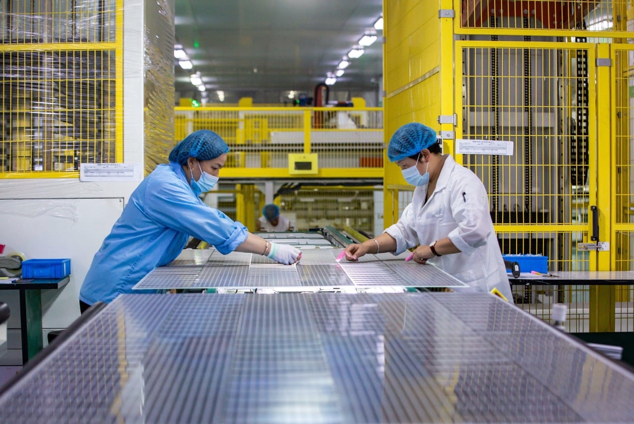 Montaż paneli na chińskiej farmie solarnej Robotnicy w kaskach montujący panele fotowoltaiczne na pustynnej farmie