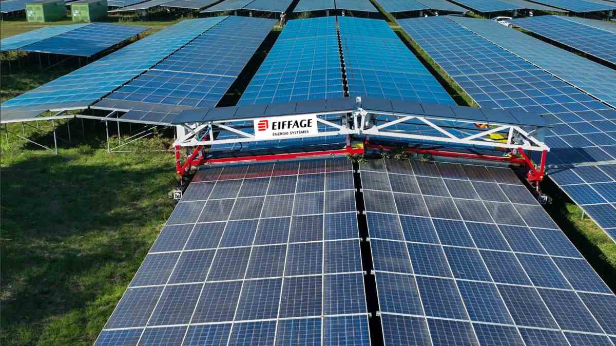 kilka robotów jednocześnie myje rząd paneli na pochyłej farmie fotowoltaicznej